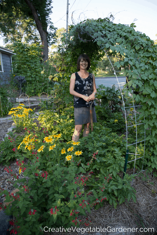 woman under trellis in photo of vegetable garden